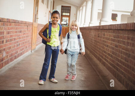 Sorridendo gli alunni tenendo le mani sul corridoio Foto Stock