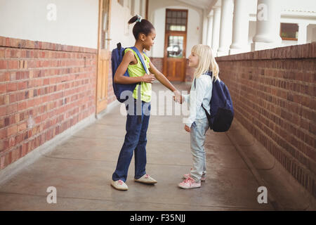 Sorridendo gli alunni tenendo le mani sul corridoio Foto Stock