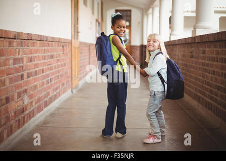 Sorridendo gli alunni tenendo le mani sul corridoio Foto Stock