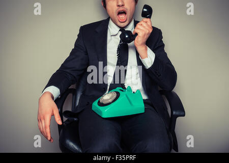 Sorpreso giovane imprenditore della sedia per ufficio è sul telefono Foto Stock