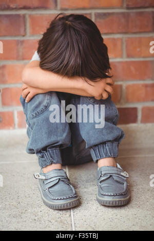 Sconvolto lonely bambino seduto da se stesso Foto Stock