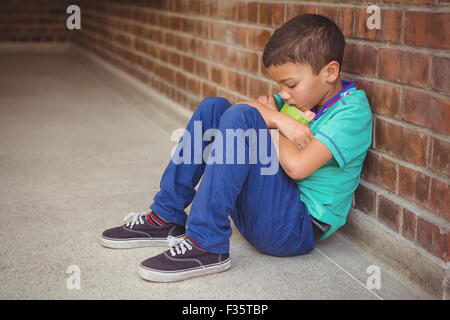 Sconvolto lonely bambino seduto da se stesso Foto Stock