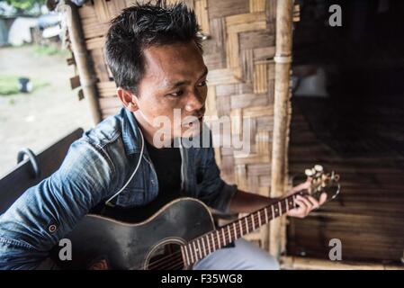 Un rifugiato kachin suona la chitarra in un campo di rifugiati in stato Kachin, Myanmar Foto Stock
