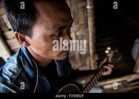 Un rifugiato kachin suona la chitarra in un campo di rifugiati in stato Kachin, Myanmar Foto Stock