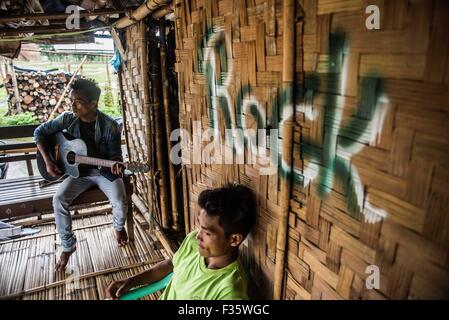 Un rifugiato kachin suona la chitarra in un campo di rifugiati in stato Kachin, Myanmar Foto Stock