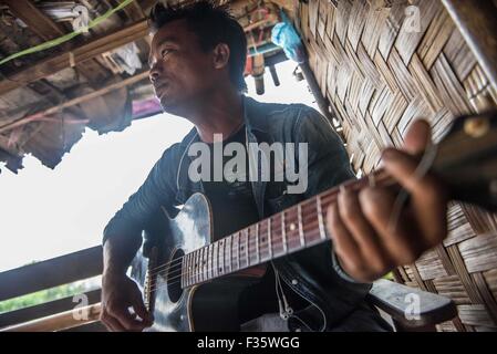 Un rifugiato kachin suona la chitarra in un campo di rifugiati in stato Kachin, Myanmar Foto Stock