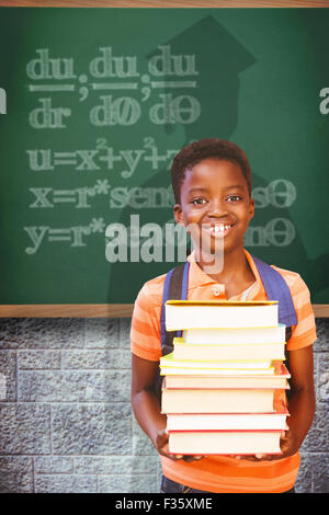 Immagine composita di carino piccolo ragazzo il trasporto di libri in biblioteca Foto Stock