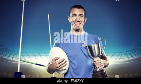 Immagine composita del ritratto di sorridere giocatore di rugby trofeo holding e la sfera Foto Stock