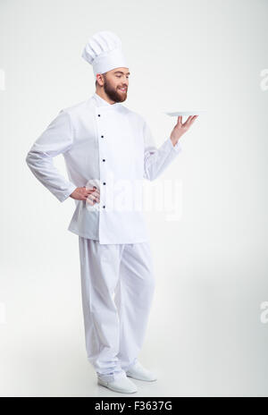 Ritratto di un maschio felice chef cucinare in piedi con la piastra isolata su un backgorund bianco Foto Stock