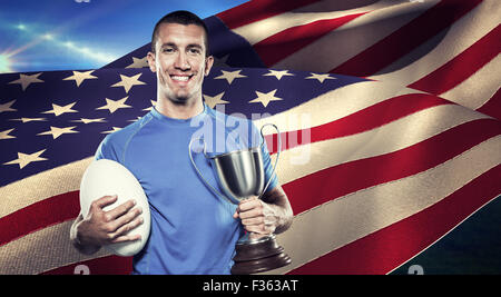 Immagine composita del ritratto di sorridere giocatore di rugby trofeo holding e la sfera Foto Stock