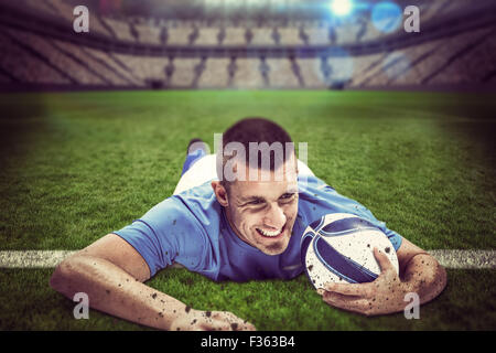 Immagine composita di fiduciosa giocatore di rugby che giace di fronte con sfera Foto Stock