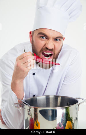 Ritratto di un maschio divertenti chef di cucina azienda pepe rosso Foto Stock