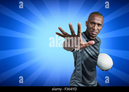 Immagine composita di close-up ritratto di uno sportivo gesticolando mentre in piedi con la palla da rugby Foto Stock