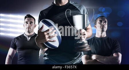 Immagine composita della sezione mediana di successo del giocatore di rugby trofeo holding e la sfera Foto Stock