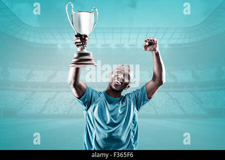 Immagine composita di felice sportivo cercando e rasserenanti tenendo trophy Foto Stock