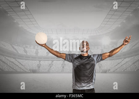 Immagine composita di fiduciosa atleta con bracci sollevati tenendo palla da rugby Foto Stock