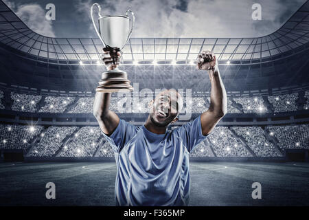 Immagine composita di felice sportivo cercando e rasserenanti tenendo trophy Foto Stock