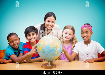Immagine composita di graziosi gli alunni e gli insegnanti guardando il globo in biblioteca Foto Stock