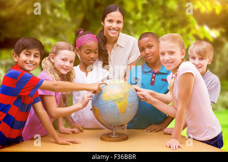 Immagine composita di graziosi gli alunni e gli insegnanti guardando il globo in biblioteca Foto Stock