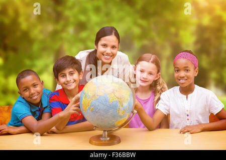 Immagine composita di graziosi gli alunni e gli insegnanti guardando il globo in biblioteca Foto Stock