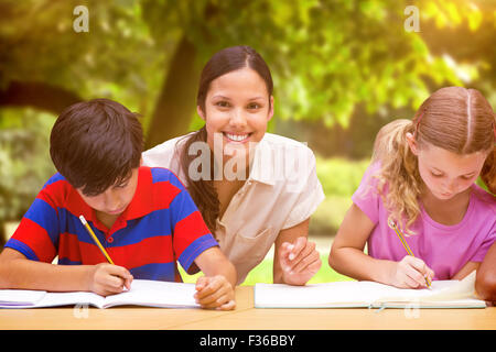 Immagine composita di pretty docente aiutare gli studenti nella libreria Foto Stock