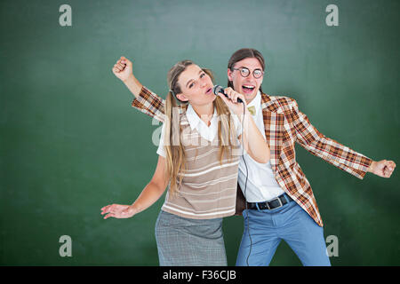 Immagine composita di felice geeky hipsters cantando con microfono Foto Stock