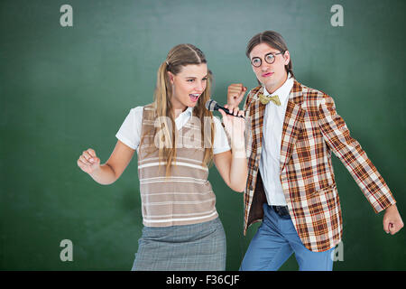 Immagine composita di felice geeky hipsters cantando con microfono Foto Stock