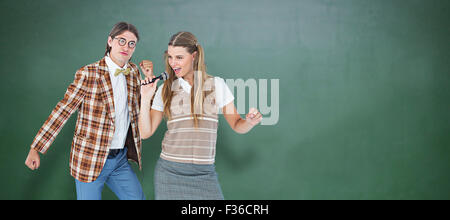 Immagine composita di felice geeky hipsters cantando con microfono Foto Stock