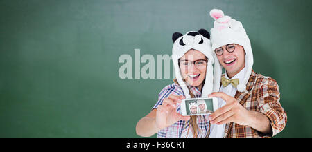 Immagine composita di geeky hipster giovane tenendo selfie con smart phone Foto Stock