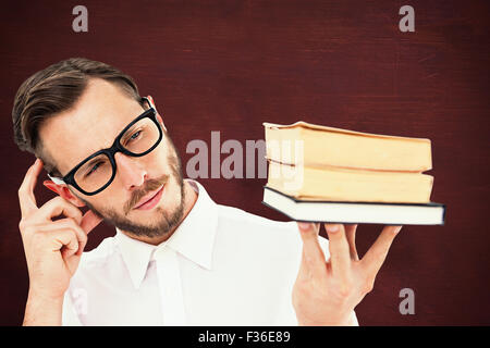 Immagine composita di geeky giovane guardando alla pila di libri Foto Stock