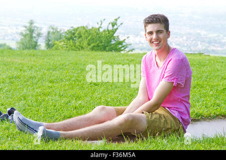 Giovani, felice uomo seduto su un prato Foto Stock