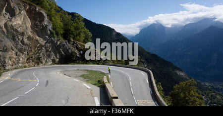 Un ciclista round uno dei famosi forcine mentre scendendo Alpe d'Huez nella tarda estate del sole Foto Stock
