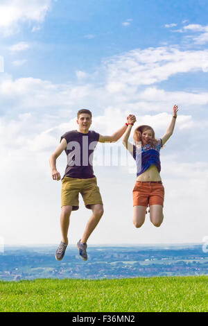 Coppia giovane saltare in aria in alto Foto Stock