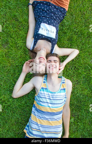 Felice una giovane coppia giacendo in erba Foto Stock