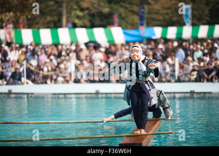 Attore che indossa la maschera tradizionale yukata Giapponesi in equilibrio su registro quadrato su acqua Foto Stock