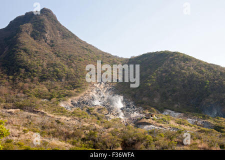 Sorgente calda naturale aumento di vapore dalle rocce circondato da montagne Foto Stock