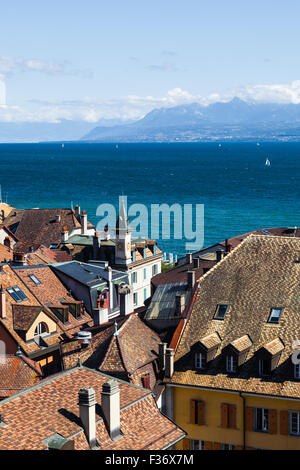 Vista sui tetti di Nyon in Svizzera, guardando attraverso il lago di ginevra verso le Alpi francesi Foto Stock