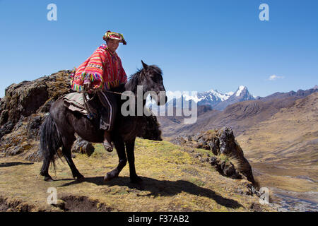 Indio guide di montagna con il poncho colorato cavalcare, tra le montagne delle Ande, Provincia di Cusco, Perù Foto Stock