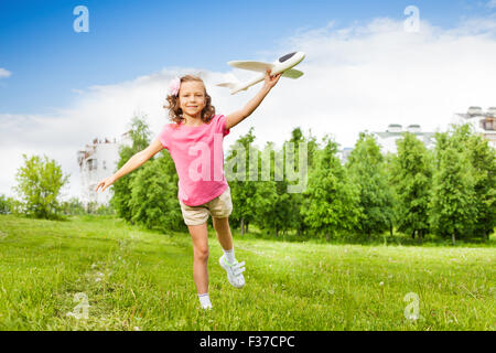 Felice Tiene ragazza aeroplano giocattolo con una gamba in alto Foto Stock