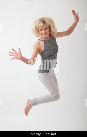 Ritratto di una donna bionda saltare in aria in un studio. Foto Stock