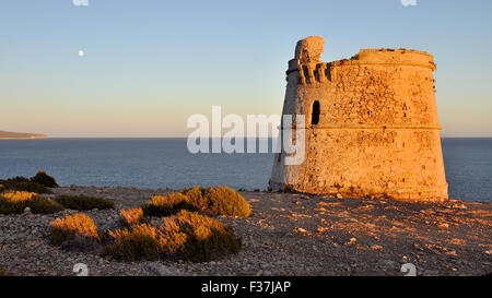 Vista al tramonto di Torre des Garroveret tower con la luna in distanza, a Es Cap de Barbaria, Formentera (Isole Baleari) Foto Stock