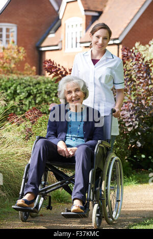 Ritratto del caregiver spingendo Senior donna in sedia a rotelle Foto Stock