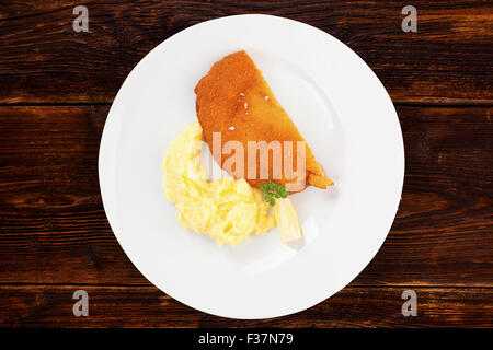 Deliziosa la Wiener Schnitzel con purè di patate su piastra su sfondo di legno, vista dall'alto. Tradizionale cucina europea. Foto Stock