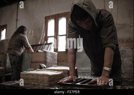 Fabbrica di carta di Jungshi, Thimphu, Bhutan. Un uomo comprime la carta fatta a mano durante il processo di produzione della carta. La carta è puramente fatta a mano in modo da vende a. Foto Stock