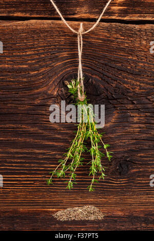 Fresco e Secco timo cantato sul legno rustico sfondo. Delizie di erbe aromatiche. Foto Stock