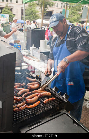 L'uomo la cottura di salsicce sul barbecue grill - USA Foto Stock
