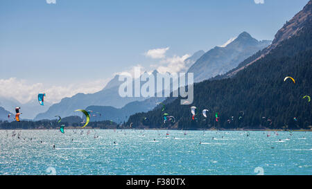 Paesaggio di montagna con un sacco di kitesurf e windsurf in movimento in un lago. Essi utilizzano il vento per spostare le loro schede sul w Foto Stock