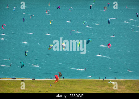 Immagine con un sacco di kitesurf e windsurf in movimento in un lago. Essi utilizzano il vento per spostare le loro commissioni sull'acqua. Foto Stock