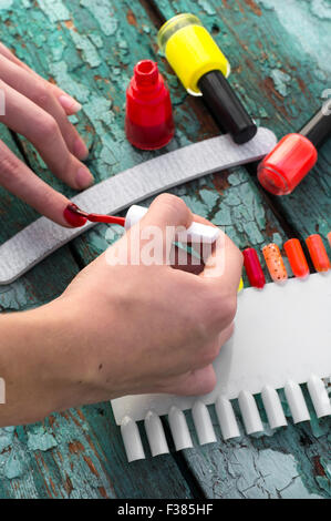 Tubi con smalto per unghie di diversi colori su un vecchio sfondo di legno Foto Stock