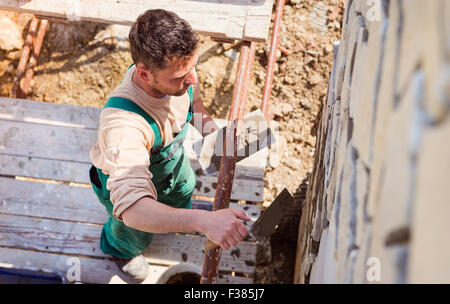 L'uomo mettendo pietre naturali su una parete Foto Stock